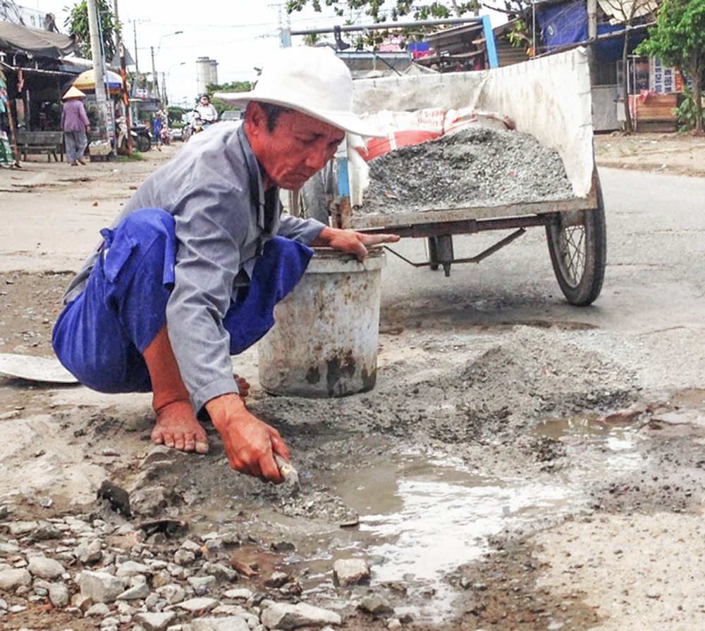 Ông Hai Dân đang giặm vá những đoạn đường bị hư hỏng